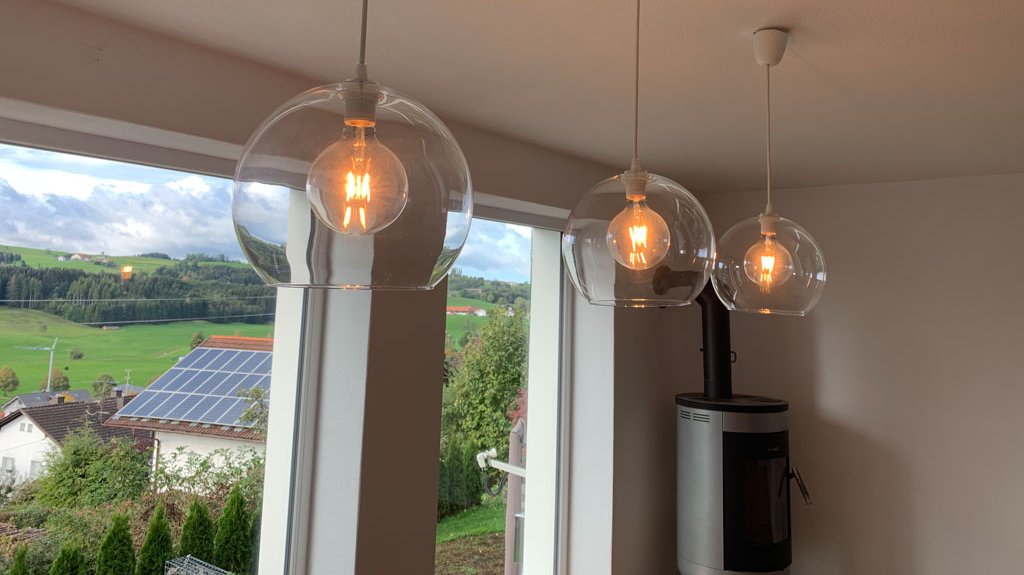 Beleuchtungstechnik durch moderne Lampen in einem modernen Wohnhaus - im Hintergrund ist ein Pelletofen zu sehen