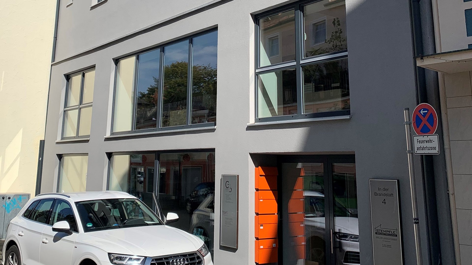 Bürogebäude in Kempten von außen. Davor steht ein weißes Auto